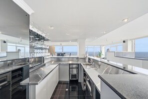 Una cocina moderna con una isla central, electrodomésticos de acero inoxidable y vista al océano.