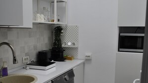 Una cocina compacta con lavadora, cafetera y microondas.