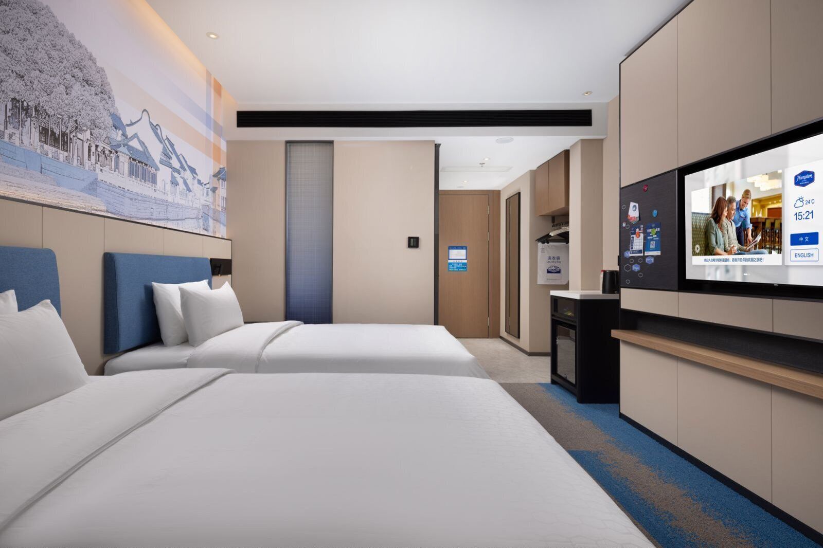 Habitación de hotel con dos camas, un televisor y un escritorio con una computadora.