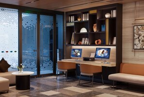 Una biblioteca moderna con dos monitores de ordenador, estanterías y asientos cómodos.