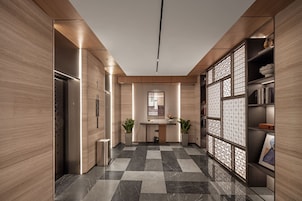 A modern hallway with a checkered floor, wooden walls, a reception desk, and a decorative screen.