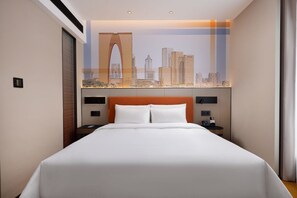 A hotel room with a large bed, a cityscape mural on the wall, and a modern headboard.