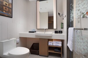 Un baño moderno con lavamanos blanco, espejo, inodoro y zona de ducha.