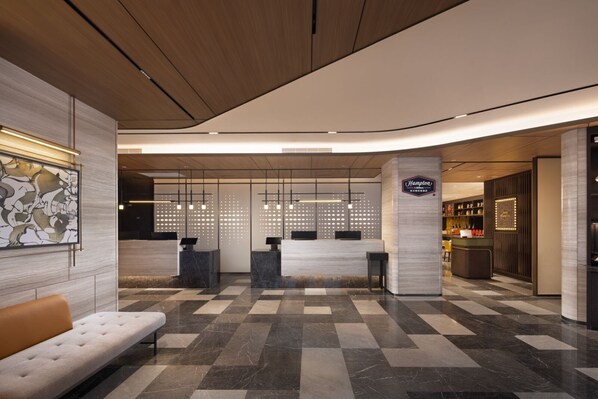 A hotel reception area with a check-in counter, seating area, and a bar.