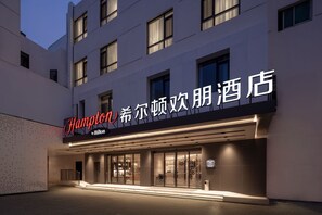 A hotel exterior with a sign reading 'Hampton by Hilton' and Chinese characters.
