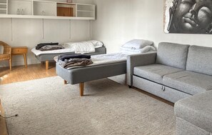 A bedroom with a grey sofa, a bed with a white mattress, a wooden nightstand, and a wall-mounted shelf with decorative items. - 3 bedroom gorgeous home in Visby (Visby)