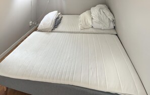 A bed with a white mattress and grey bedding, a power outlet on the wall, and a cable running along the wall. - 3 bedroom gorgeous home in Visby (Visby)