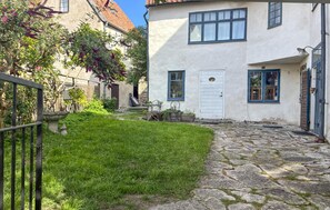 A courtyard with a stone pathway, a white building with blue trim, and a small garden area. - 3 bedroom gorgeous home in Visby (Visby)