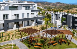 Un edificio moderno con numerosi balconi, posti a sedere all'aperto e vista sulle colline circostanti.