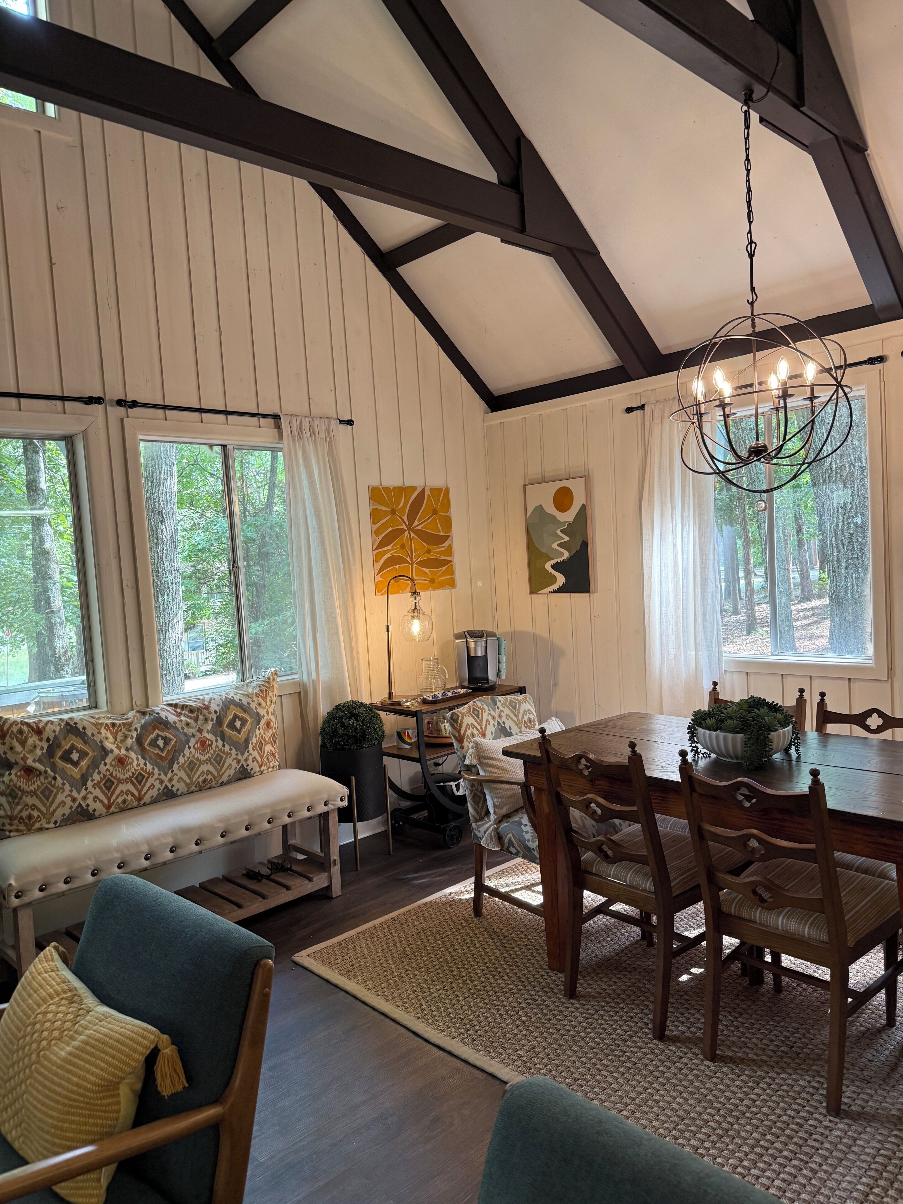 A cozy room with a wooden dining table, chairs, a bench, and a chandelier.