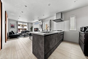 Una cocina moderna con una isla central, electrodomésticos integrados y vistas a un balcón.