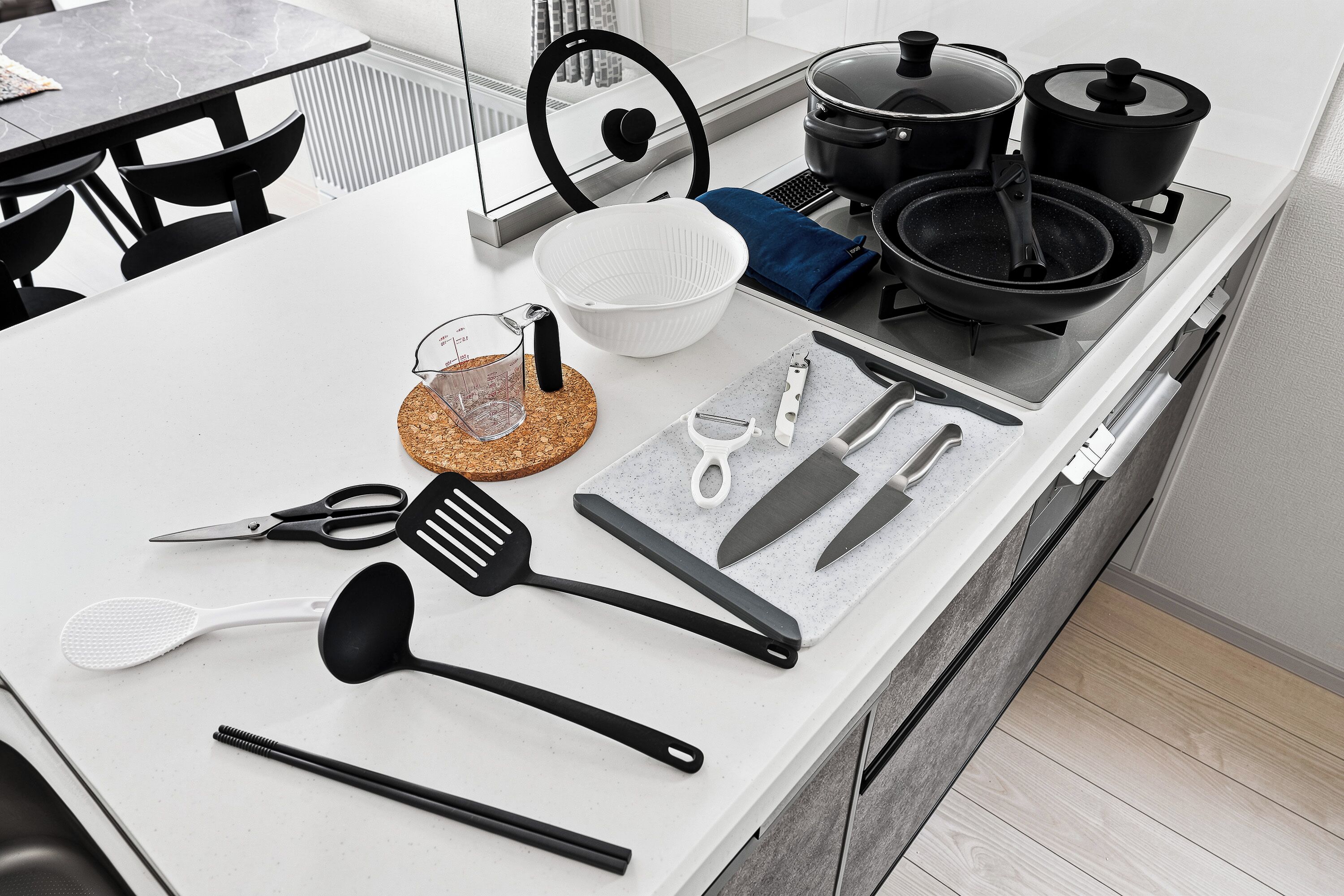 Una encimera de cocina con diversos utensilios, ollas y un vaso medidor.