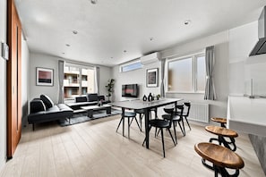 Una sala moderna con un sofá, una mesa de centro y un comedor con sillas.