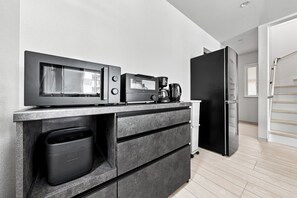 Una kitchenette equipada con microondas, cafetera y refrigerador.