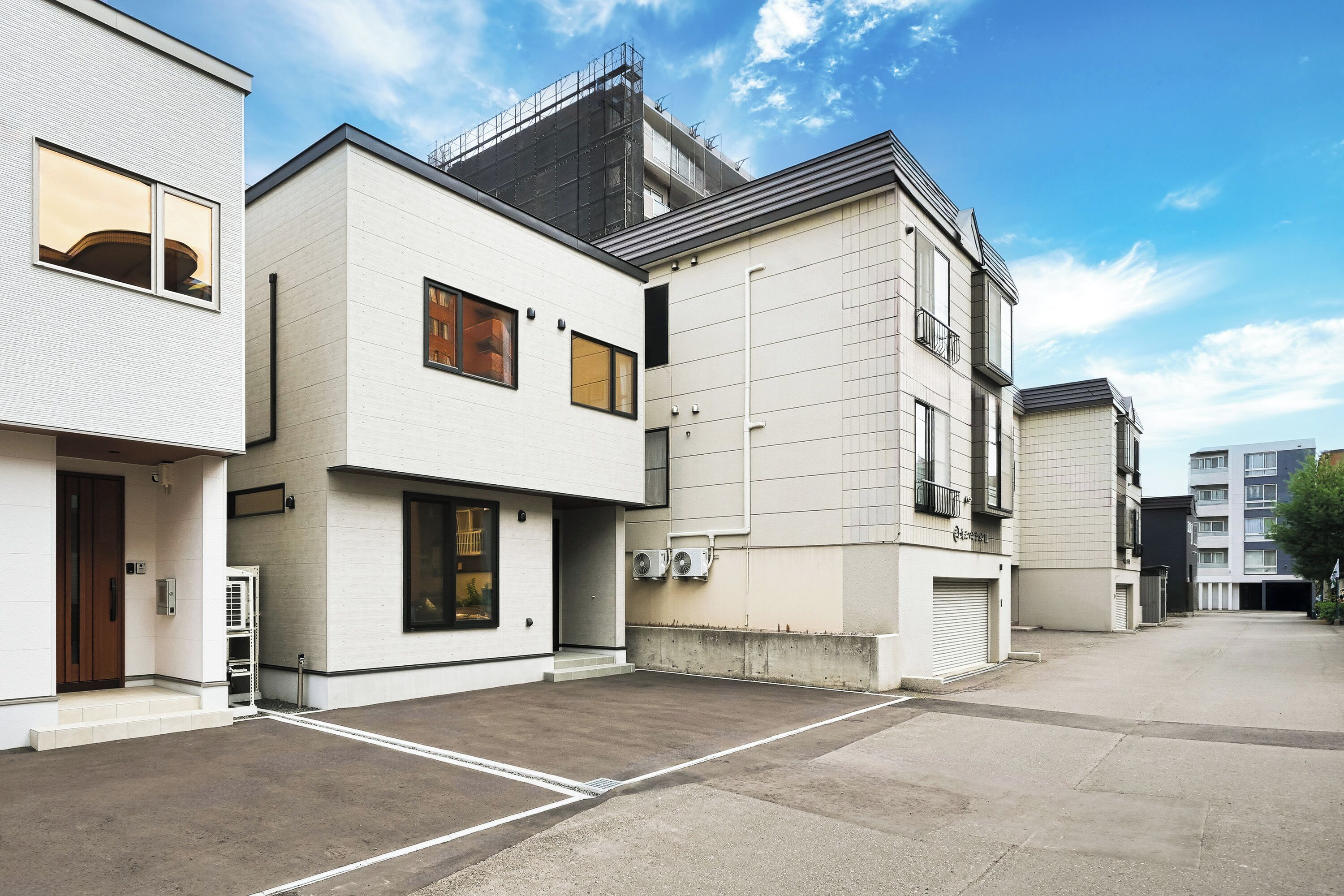 Un edificio residencial moderno con techo plano, ventanas amplias y una unidad de aire acondicionado visible.