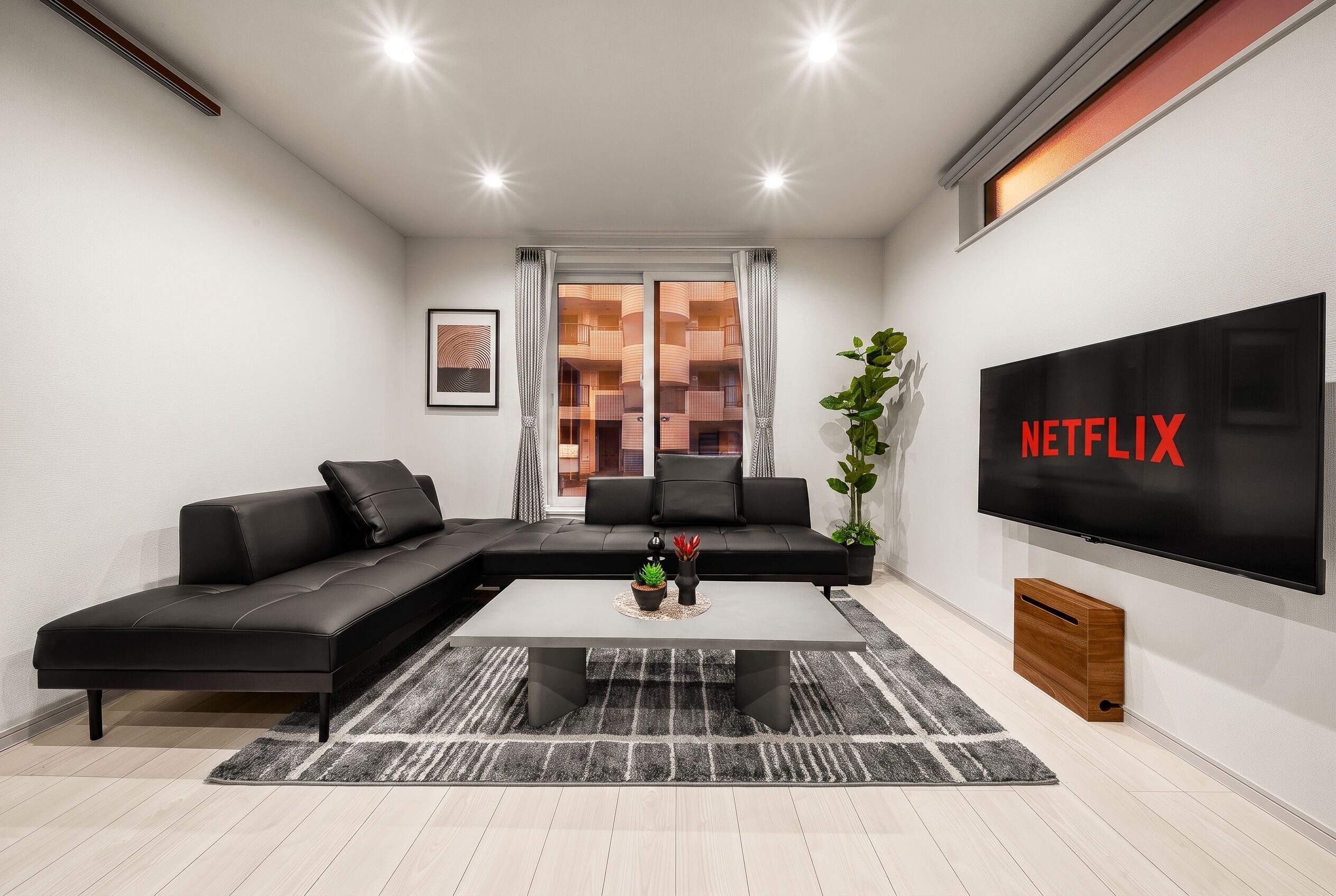 Una sala de estar moderna con un sofá modular, una mesa de centro, un televisor de pantalla plana y una planta en maceta.