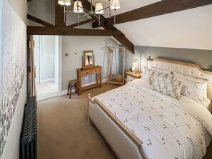 Ein Schlafzimmer mit einem großen Bett, einem Schminktisch, einem Spiegel und einem Deckenventilator.