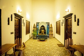 A hallway with a central statue, wooden doors, and a tiled floor.