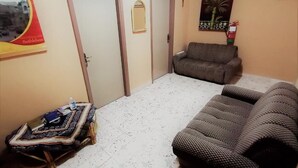Una habitación con un sofá estampado, una mesita con un objeto decorativo y una puerta con un espejo.