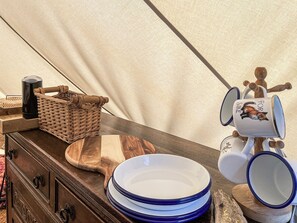 Ein Holztisch mit einer Stapel blauer Teller, einem Korbwannenweidenkorb, einer schwarzen Flasche und einer Tasse mit einem Fuchs-Motiv.