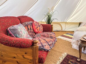 Ein gemütliches Interieur mit einer Holzsofa, verziert mit gemusterten Kissen, einem gewebten Teppich und einem Blumentopf.