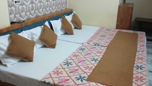 Un lit avec une couvre-lit à motifs, plusieurs oreillers et une tête de lit ornée d’un motif géométrique.