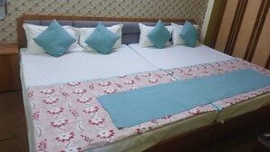 Un lit double avec une couvre-lit à motifs floraux et une couverture bleue, une tête de lit et un mur décoré d’un motif.