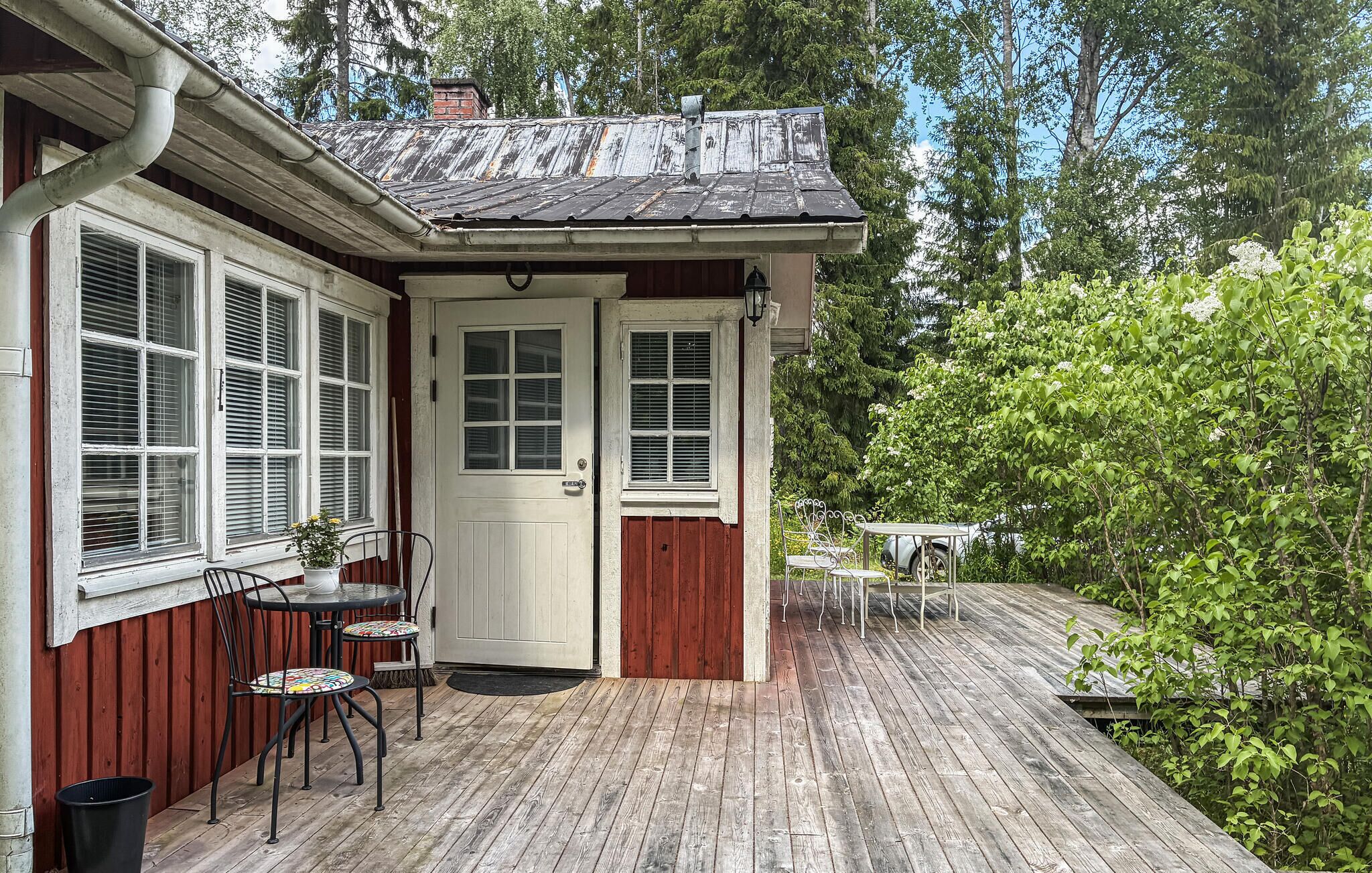 En träveranda med en dörr, fönster och utemöbler.