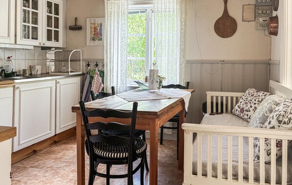 A kitchen with white cabinets, a dining table with chairs, and a crib with floral bedding.