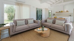 A modern living room with two sofas, a coffee table, and a kitchen area in the background. - Beautiful villa with private pool in Fontane Bianche - DiCasaInSicilia (Fontane Bianche)
