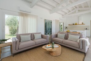 Ein modernes Wohnzimmer mit zwei Sofas, einem Couchtisch und einer Küchenzeile im Hintergrund.