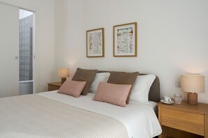 Ein Hotelzimmer mit einem Bett, zwei Nachttischen, zwei gerahmten abstrakten Bildern an der Wand.