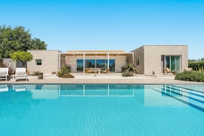Ein modernes Haus mit Swimmingpool, überdachter Terrasse und Garten.