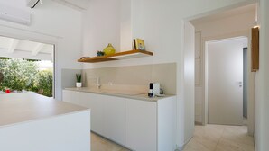 A modern kitchen with a central island, white cabinetry, and a built-in shelf above the countertop. - Beautiful villa with private pool in Fontane Bianche - DiCasaInSicilia (Fontane Bianche)