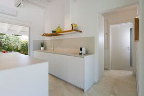 Eine moderne Küche mit einer zentralen Kochinsel, weißen Schränken und einem eingebauten Regal über der Arbeitsplatte.