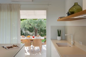Une cuisine moderne avec un coin repas, une grande fenêtre et une vue sur un jardin.