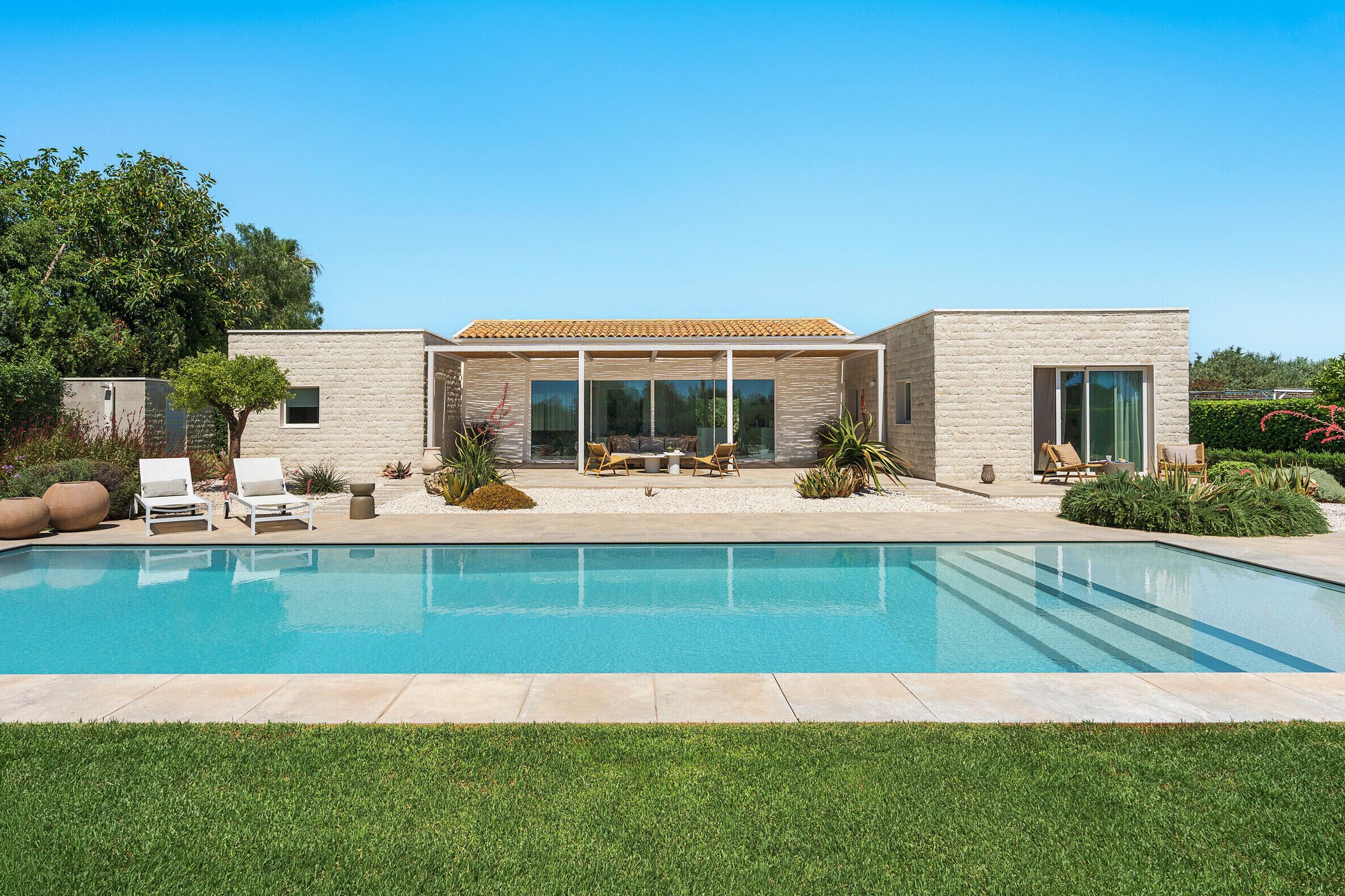 A modern house with a swimming pool, outdoor seating, and a well-maintained garden.