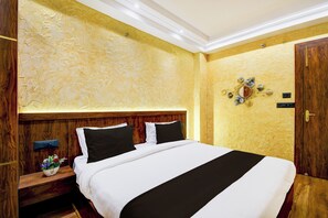 Habitación de hotel con una cama grande, cabecera de madera, una mesita de noche con lámpara y un adorno en la pared.