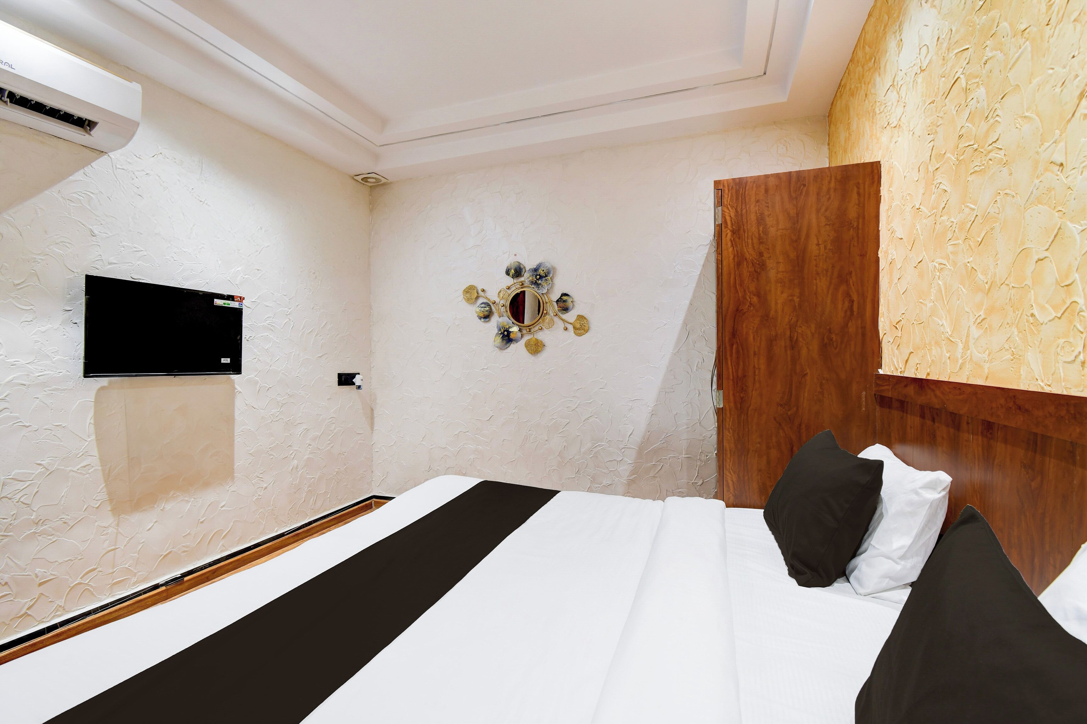 Une chambre d’hôtel comprenant un lit, un téléviseur à écran plat fixé au mur et un élément décoratif mural.