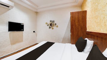 Une chambre d’hôtel comprenant un lit, un téléviseur à écran plat fixé au mur et un élément décoratif mural.