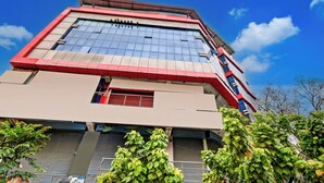 A multi-story building with a prominent red and beige facade, large windows, and a flat roof. - Super Hotel O Prayagraj Junction (Prayagraj)