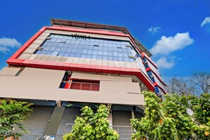 Un edificio de varios pisos con una fachada destacada en rojo y beige, ventanas amplias y techo plano.