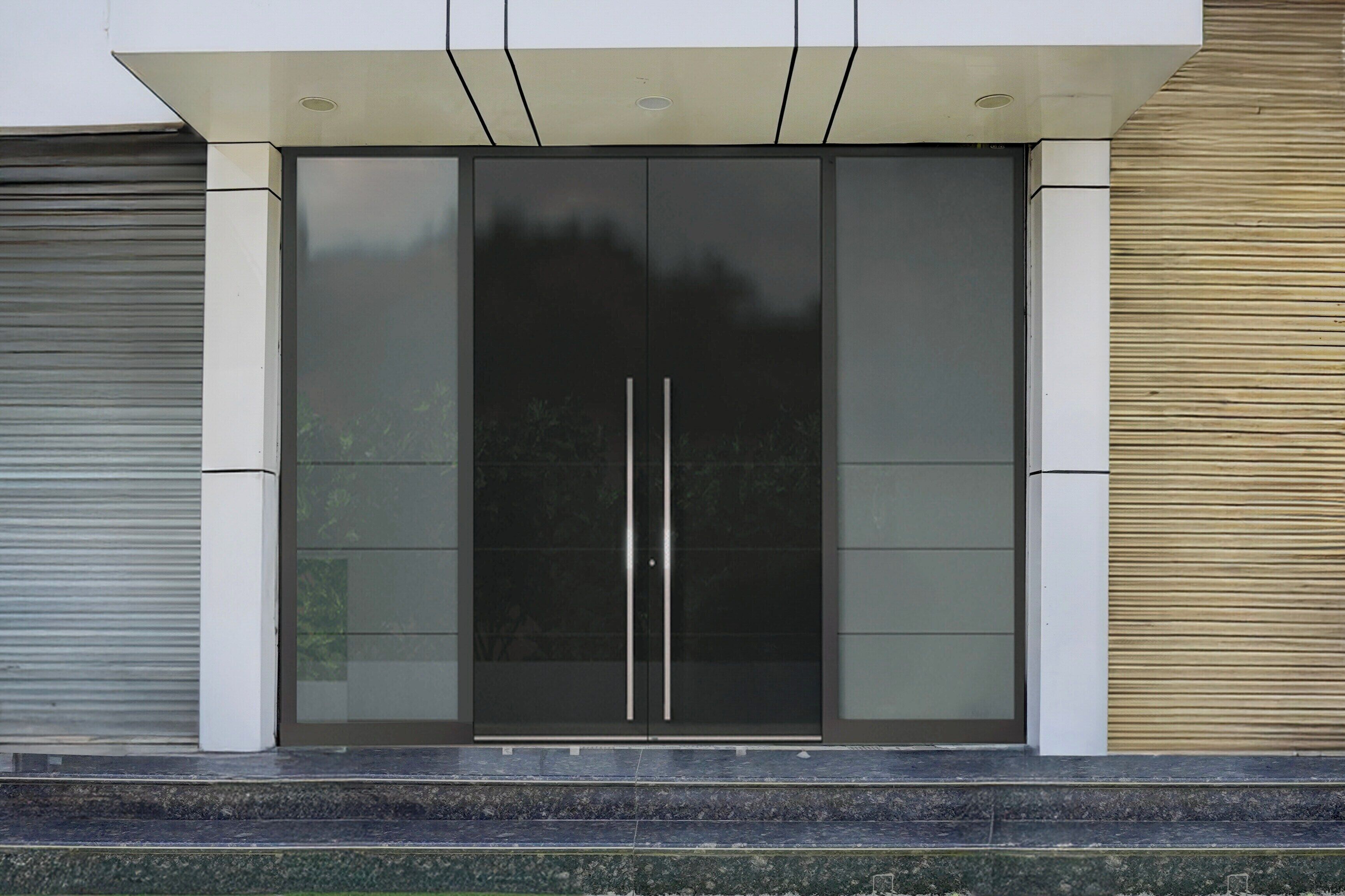 Entrada de un edificio moderno con puerta de cristal y estructura metálica.