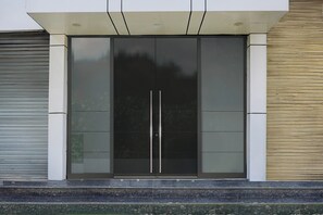 Entrada de un edificio moderno con puerta de cristal y estructura metálica.