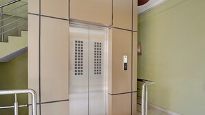 Um elevador com painel de comando e extintor de incêndio fixado na parede.