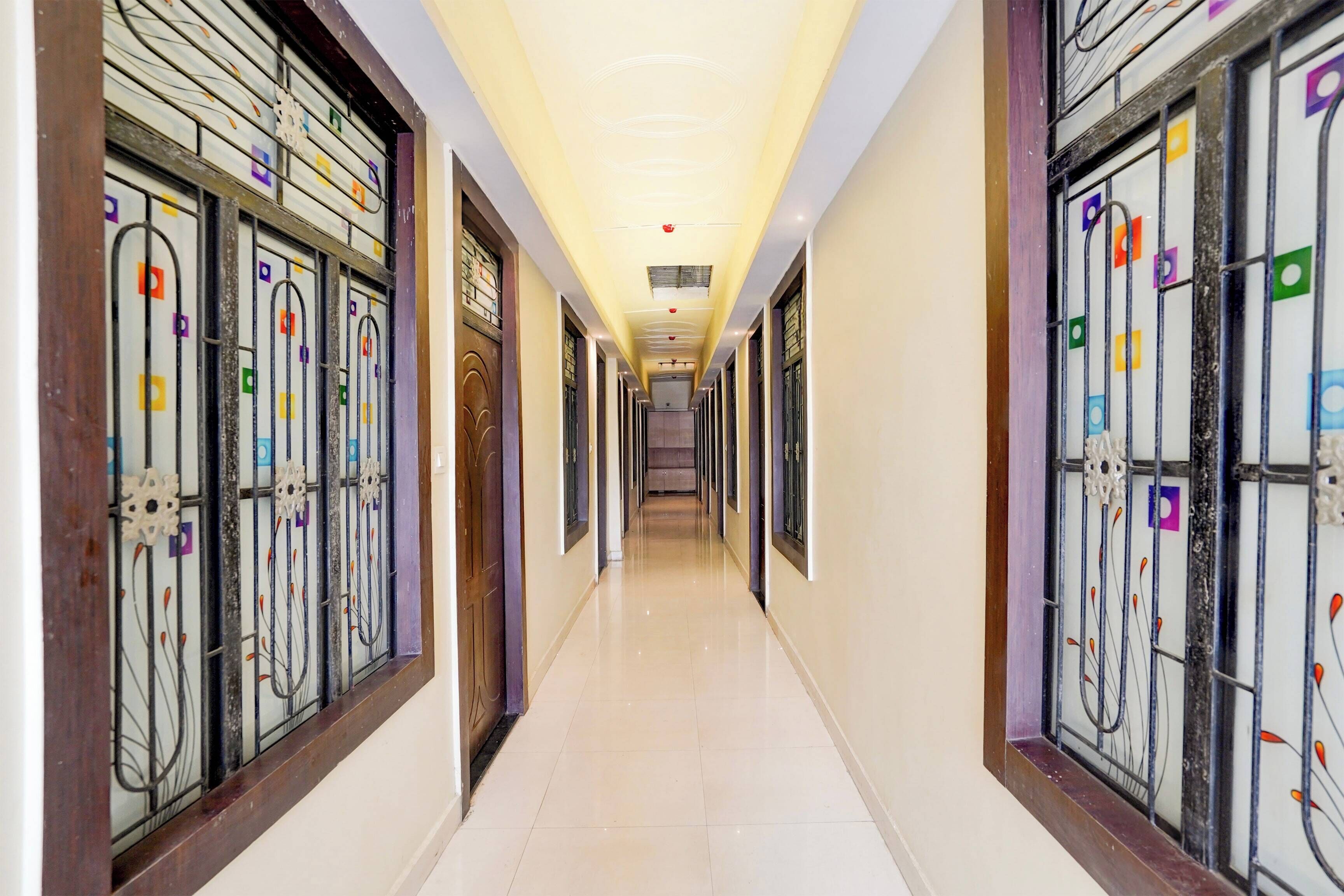 Un couloir d’hôtel avec un sol carrelé, des grilles en métal décoratives et un plafond doté d’un éclairage encastré.