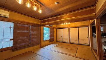 Una habitación japonesa tradicional con suelo de tatami, puertas correderas e iluminación colgante en el techo.