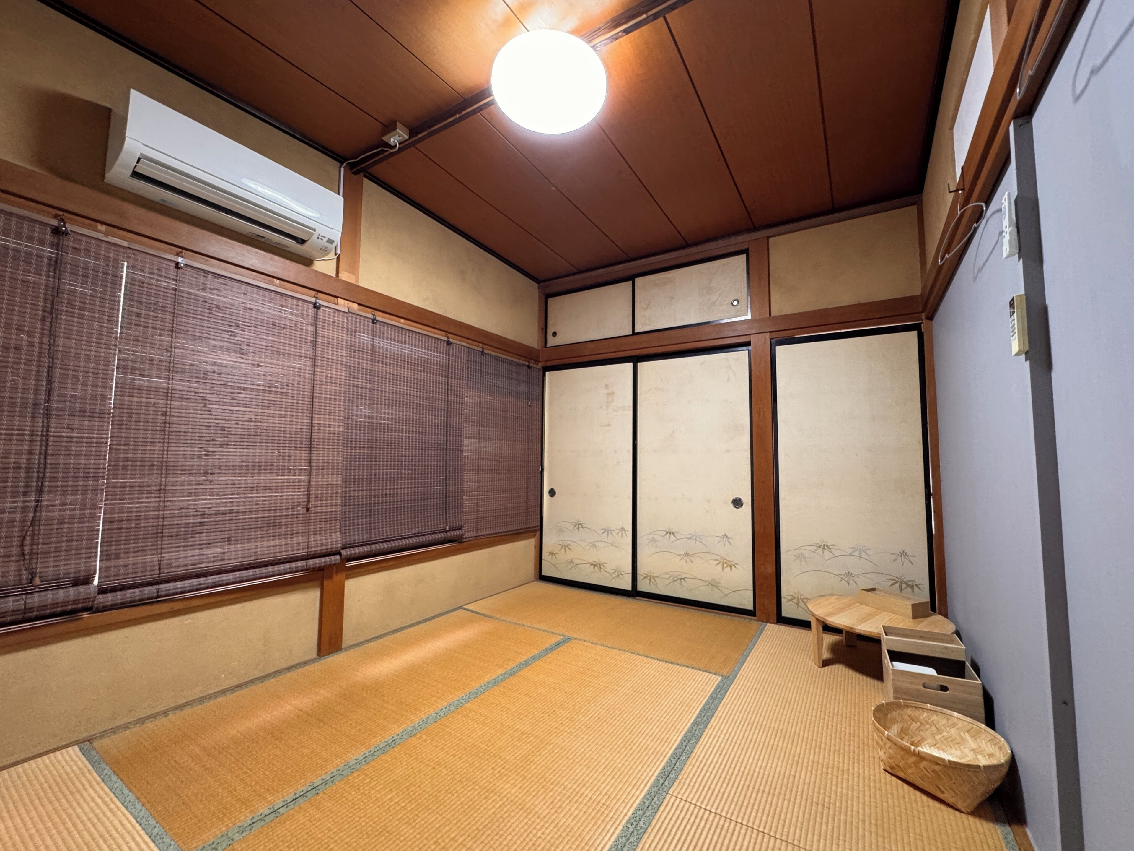 A traditional Japanese room with tatami flooring, sliding doors, and a ceiling fan.
