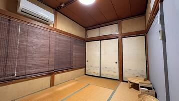 A traditional Japanese room with tatami flooring, sliding doors, and a ceiling fan.