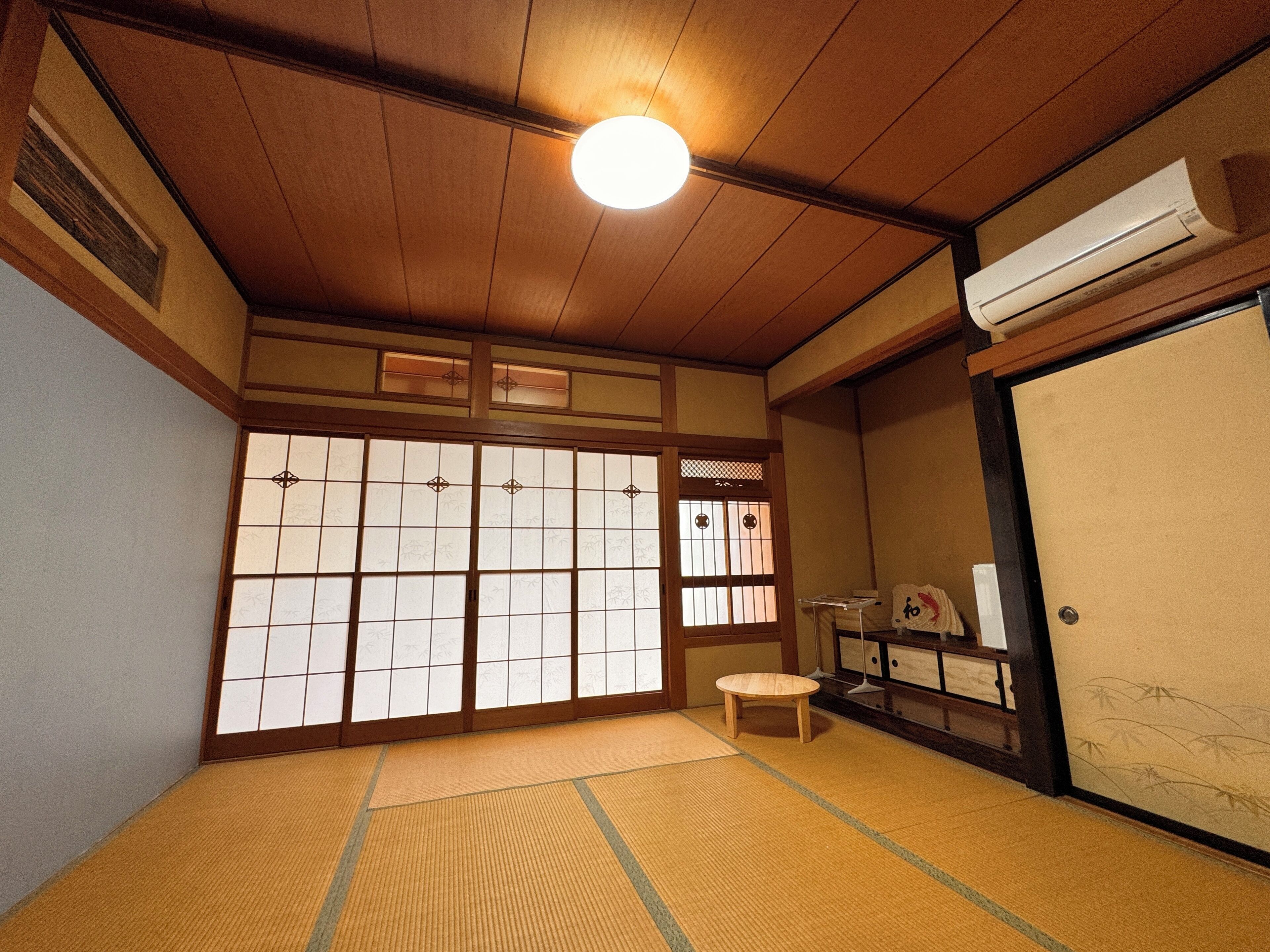 A traditional Japanese room with tatami flooring, sliding doors, and a ceiling fan.
